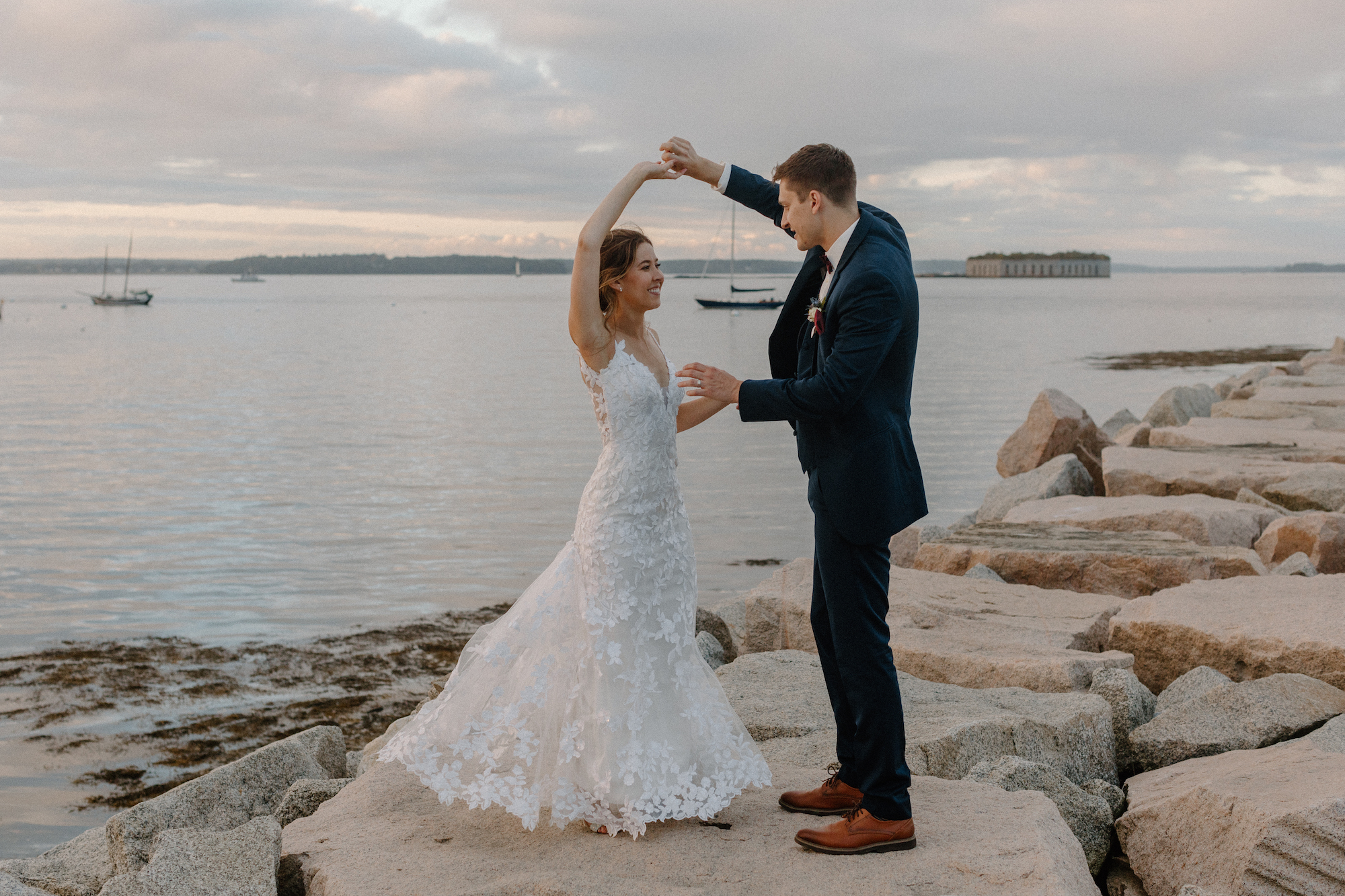 Bride and groom dancing on rocks on water in Portland, Maine