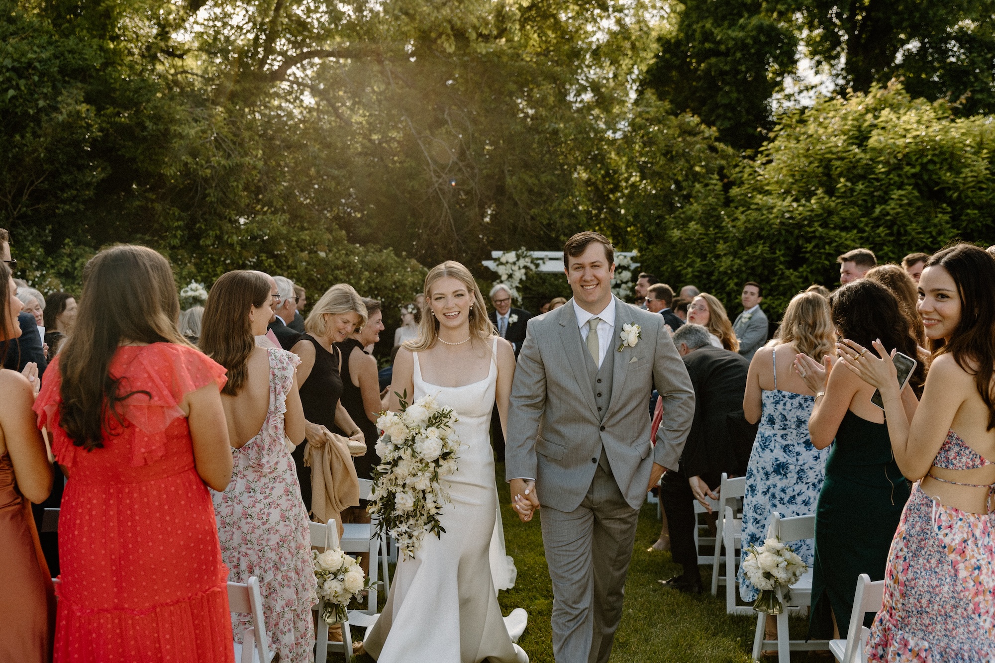 Bride and groom walking up aisle smiling on Cape Cod
